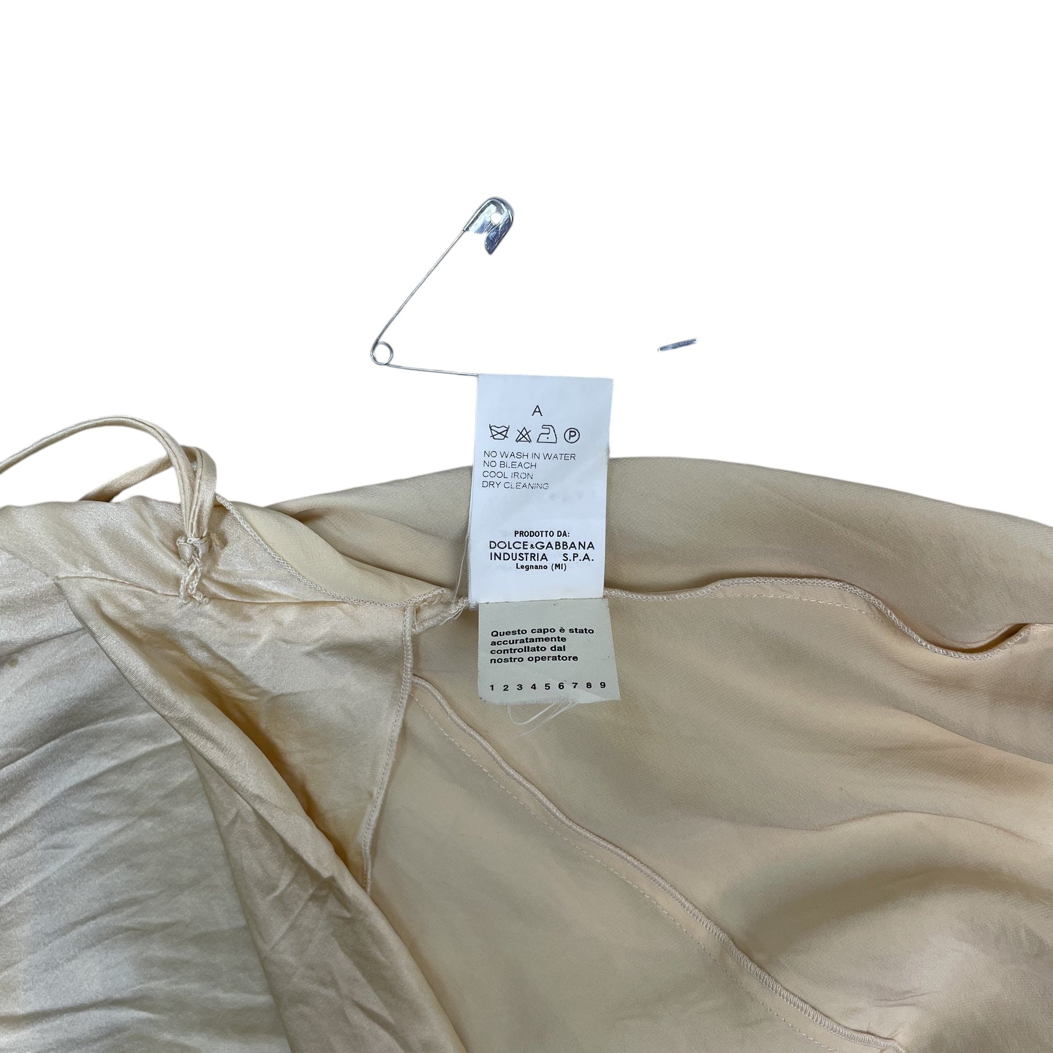 Zenno Archive Dolce & Gabbana silk dress care label and safety pin detail on a textured white background