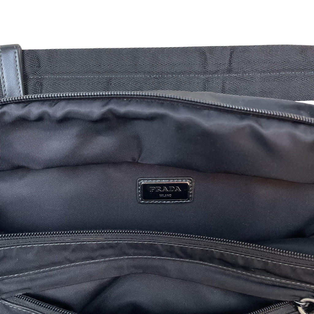 Zenno Archive Prada SS18 black nylon belt bag interior featuring the Prada Milano logo plaque and zippered compartments.