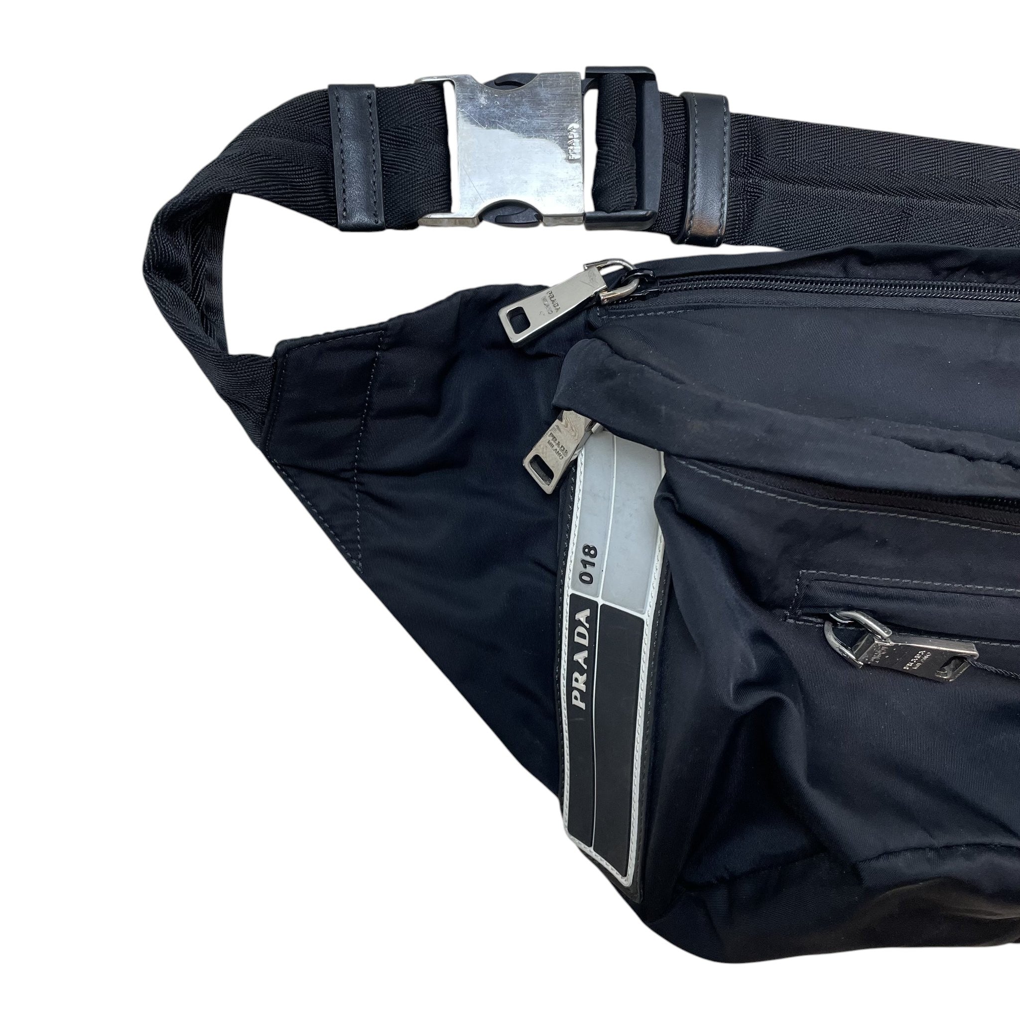 Zenno Archive Prada SS18 018 black nylon belt bag featuring a silver-tone buckle and branded zipper pulls.